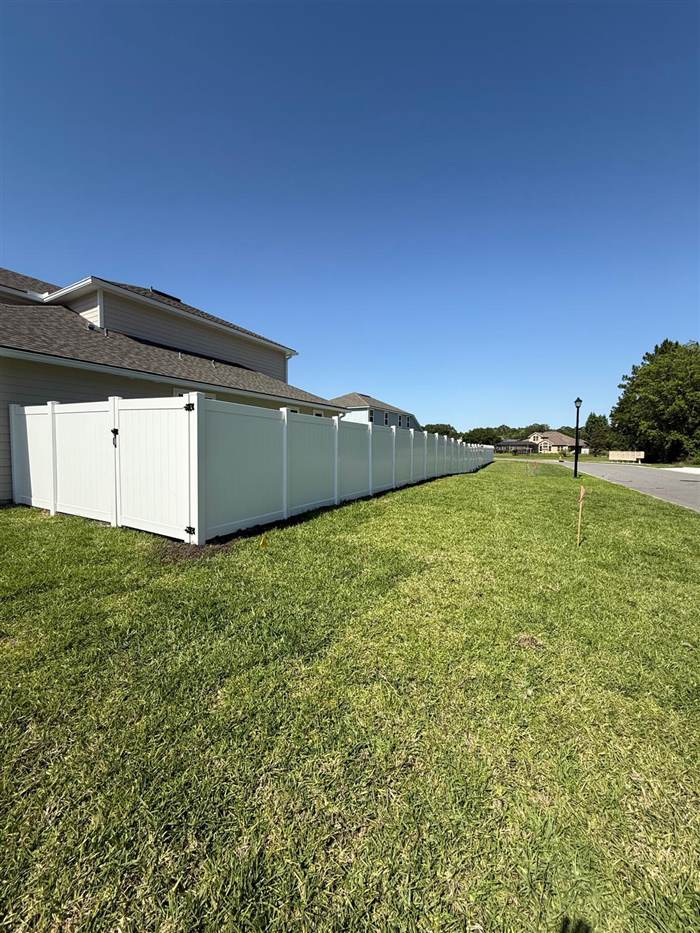 Long white vinyl fence run starting at a single gate