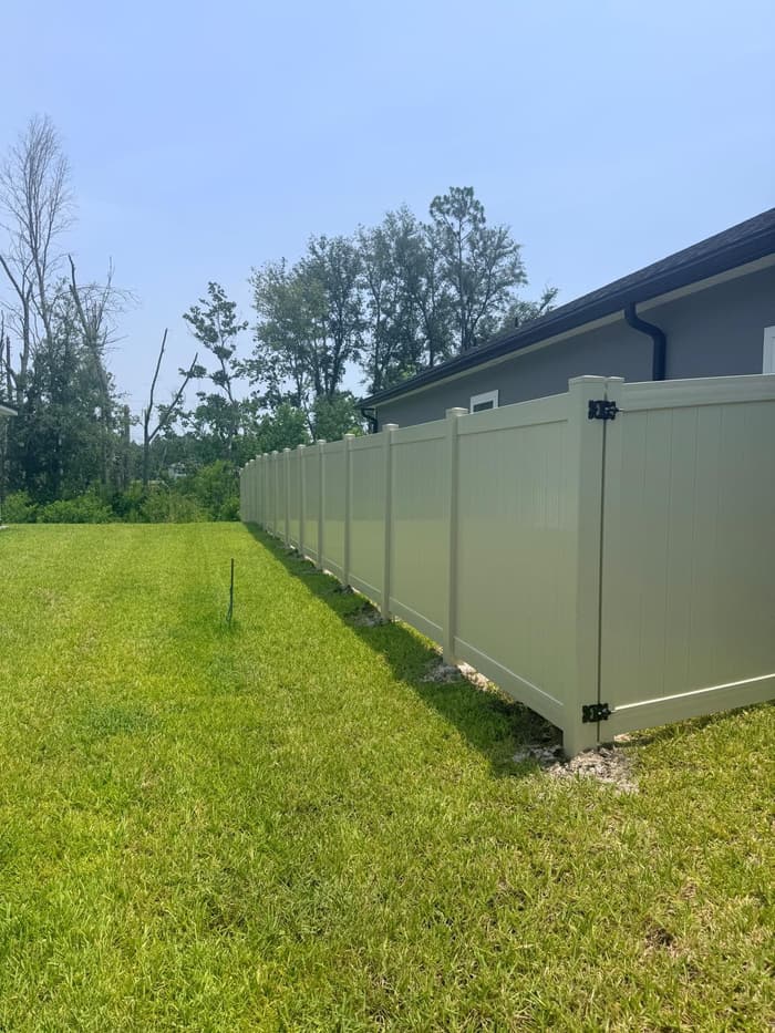 Finished tan vinyl privacy fence along a full backyard perimeter