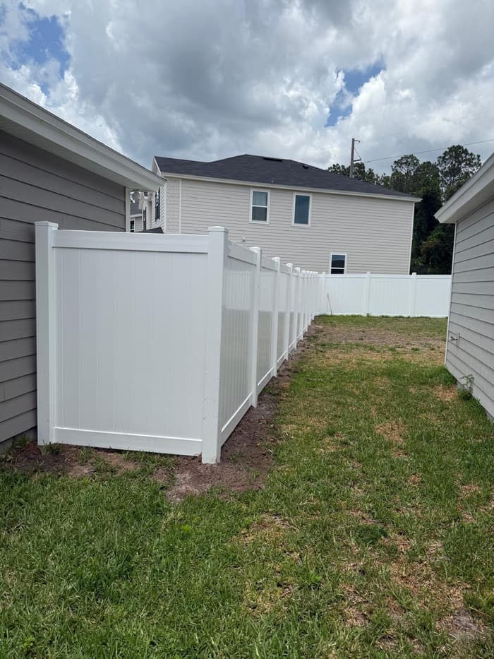 White vinyl privacy fence enclosing a backyard next to the home