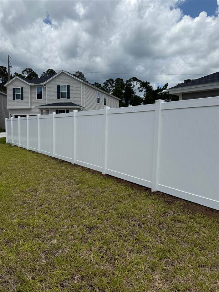 Long run of white vinyl privacy fence along a side yard